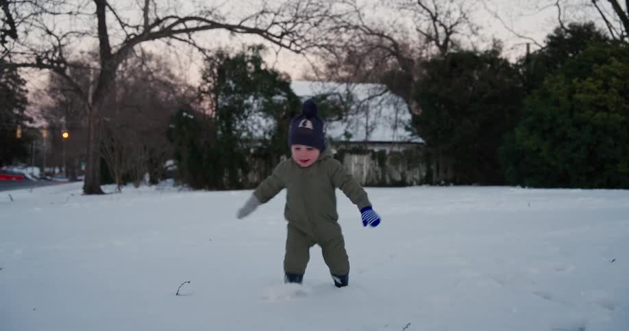 Little boy smiles as he walks through the snow in his front yard
