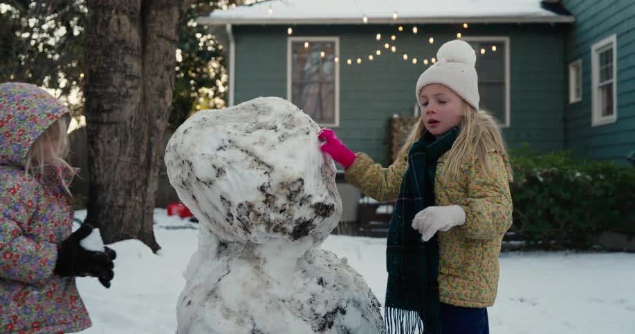 Girls making a snowman in their front yard