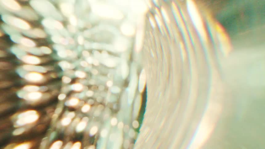 Golden light refracting through textured glass creating a swirling abstract pattern of bokeh and prism flares