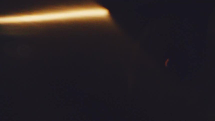 Blurred dark shape with a golden light streak against a dark background