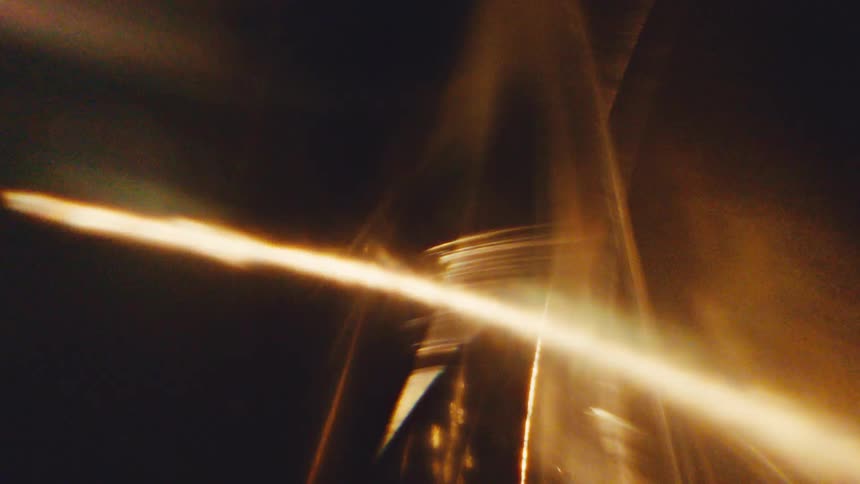 Curved streak of golden light crossing abstract shapes against a dark background