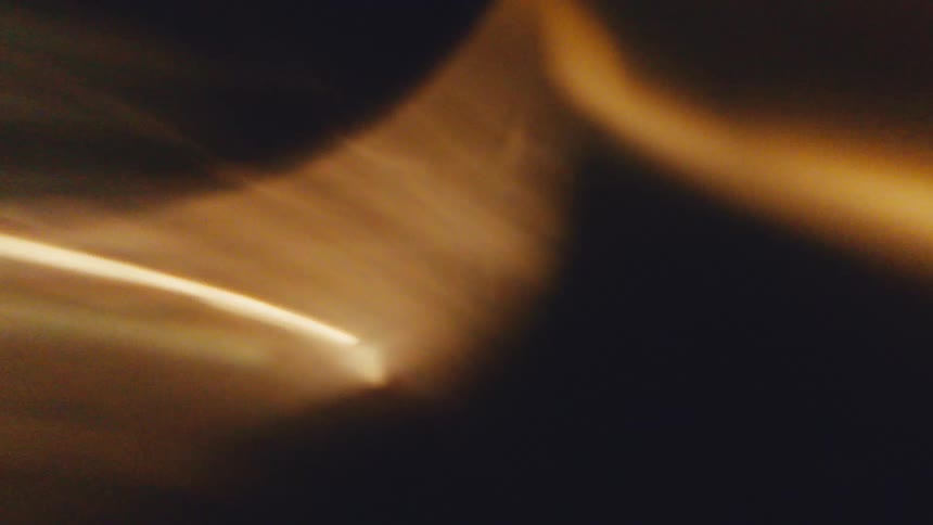 Diagonal golden light streak crossing green and dark abstract shapes