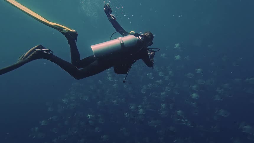 Scuba diver swims slowly through murky water