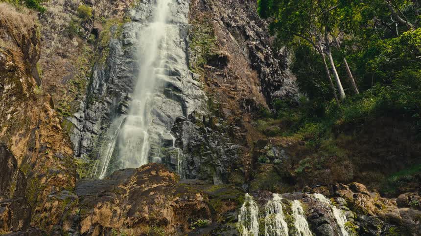 Waterfall flowing over rocks on a mountain cliff in the forest
