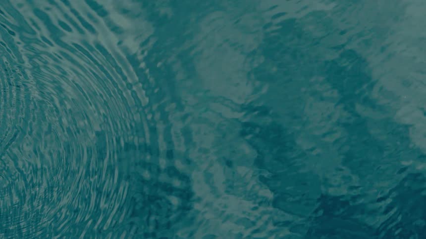 Circular ripples on the blue water surface seen from above