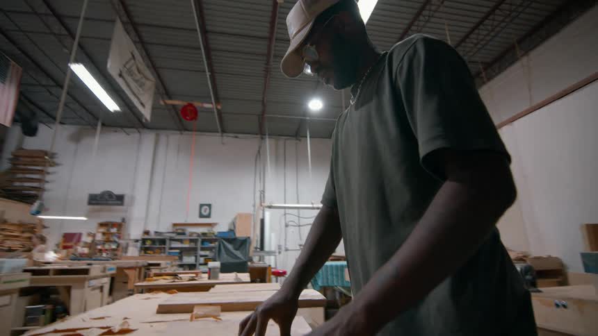 Man adjusts wooden board on workbench in toolequipped workshop