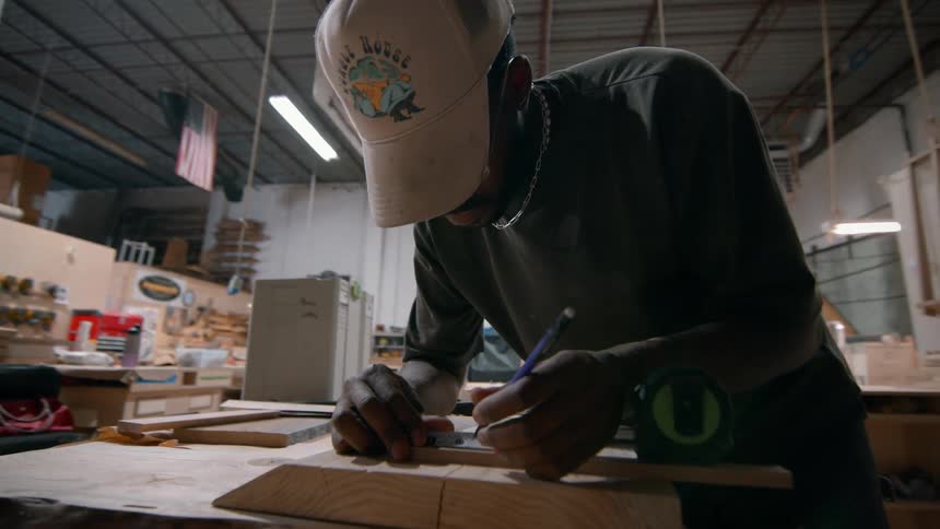 Man marking wood with pencil in carpentry workshop