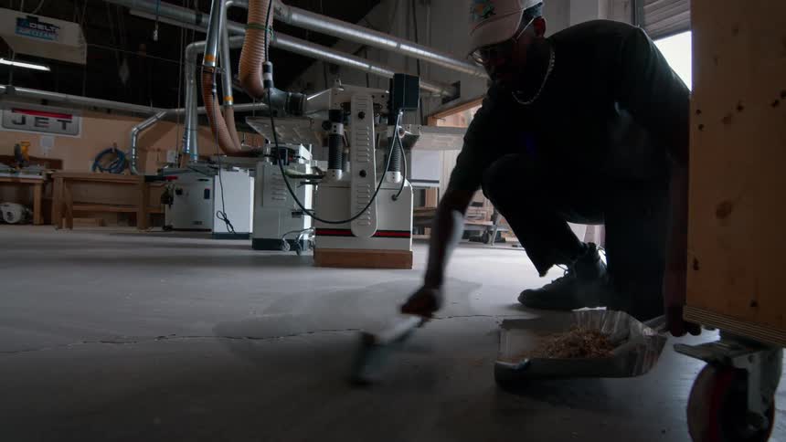 A man sweeping up a wood shop