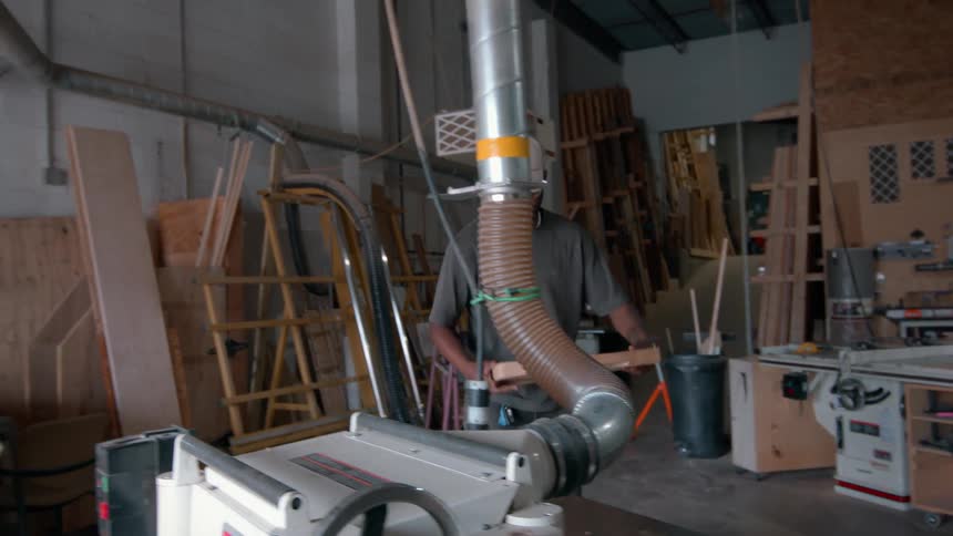The video shows a woodworker feeding a piece of timber through a thickness planer once the board passes through the machine he walks to the other side to collect it and inspects the surface