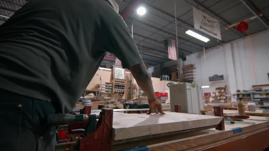 Man clamping wood slabs on workbench in woodworking shop