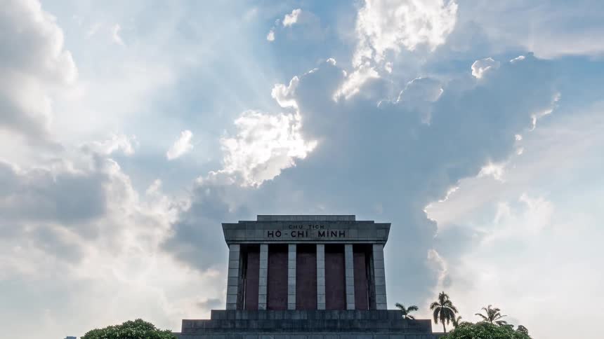 This timelapse video captures the ho chi minh mausoleum in hanoi vietnam under a dramatic sky sunlight breaks through shifting clouds creating a sense of movement and reverence over the historic monument