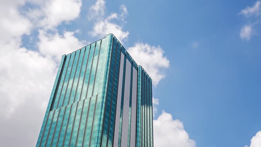 Tall building with a glass facade reflecting the blue sky