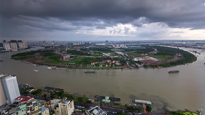 Aerial view of wide river with boats and urban area under cloudy sky