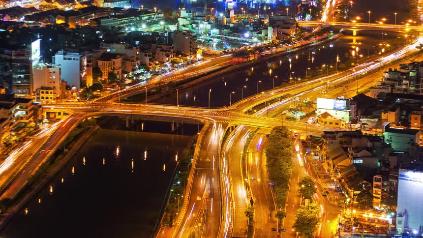 A city skyline at night with buildings illuminated by lights bright roads and surrounding areas glowing in the darkness
