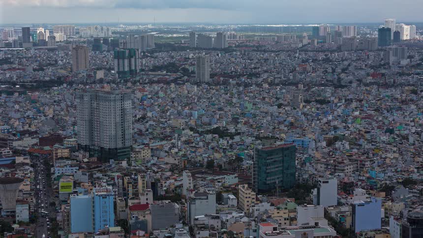 An immense and densely populated city stretches to the horizon as clouds sweep across the sky and light shifts over the thousands of buildings