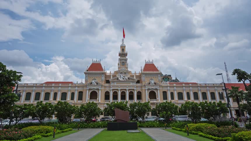 Historic building with red flag raised and front garden under cloudy sky
