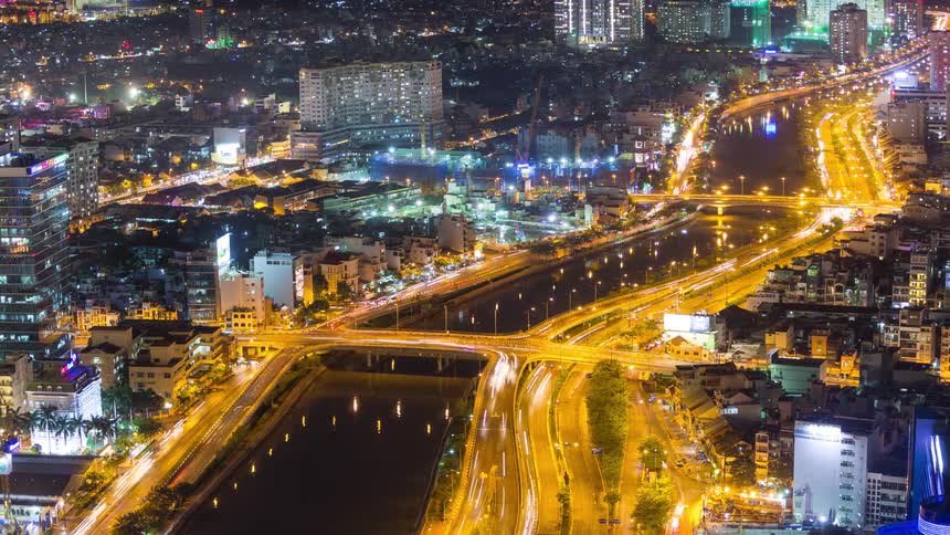 Lights glow on city buildings as traffic moves on the freeway and bridge on the coast