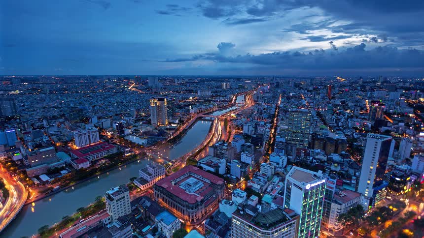 Aerial view of city at dusk with river and streets illuminated by urban lights