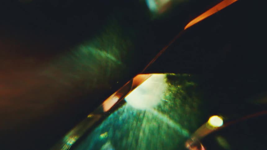 Abstract luminous reflections on translucent surface in green and bluish tones