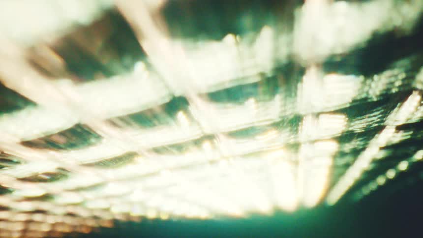 Pattern of blurred lights forming diagonal lines in golden and greenish tones