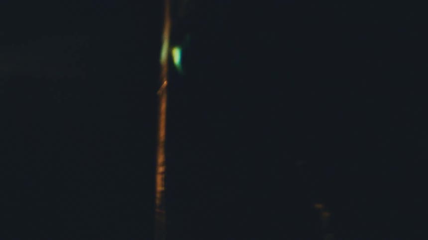 A close view shows a bright white curved light and soft golden glares that move across a dark black background creating an abstract glowing effect