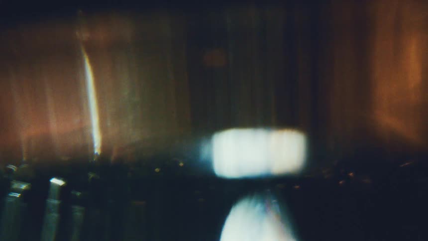 Blurred reflections on dark surface with bluish and orange light spots