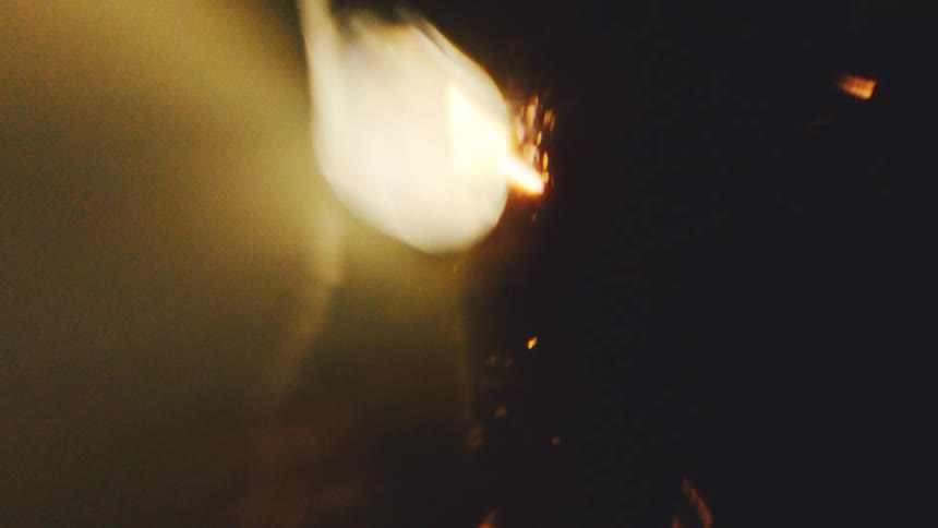 Warm ambercolored light streaks and hazy orbs dance across a dark frame creating a vintage cinematic aestheticthe light transitions from soft outoffocus glows to sharp vertical glints that suggest a flickering film projector effect