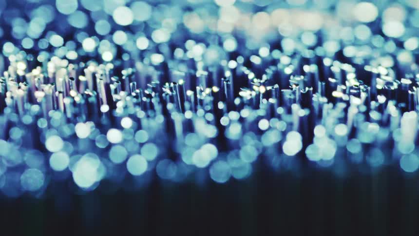 A close view shows small metallic pins that transition from a bright pink color to a cool blue as light reflects off the tops and creates a soft glowing bokeh effect against a dark background