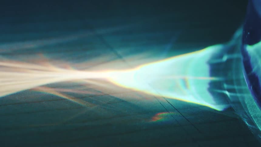 Light beam crosses dark surface forming spectrum in bluish tones