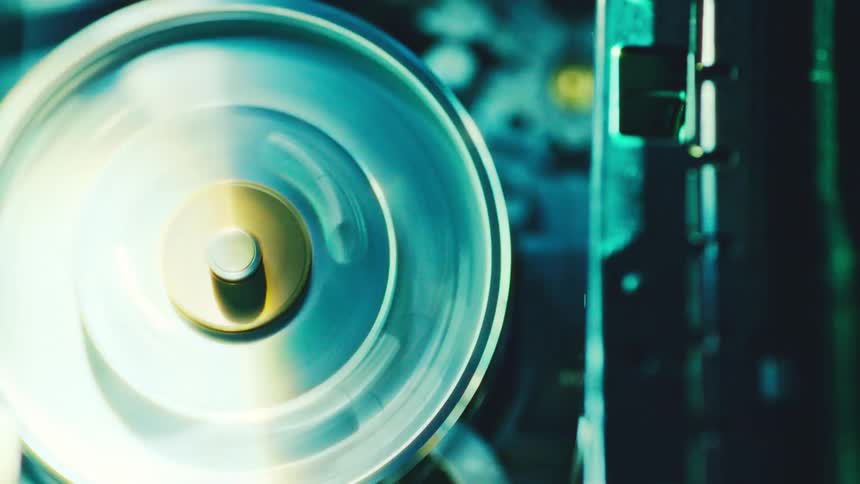 Circular metal disc illuminated in bluish tones beside industrial structure