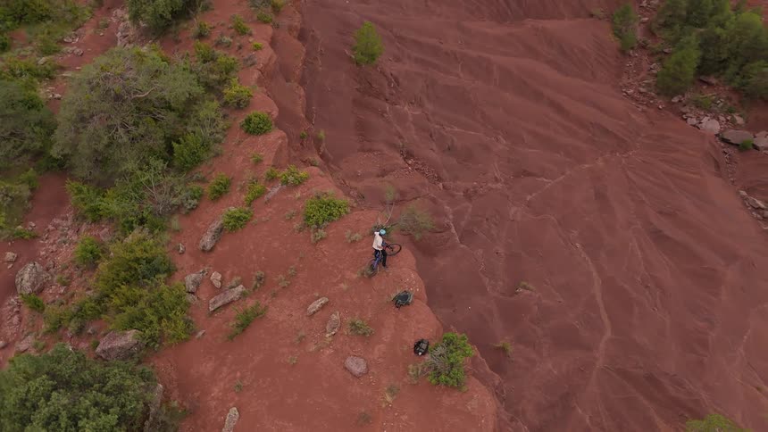 Young man on a bicycle at the edge of a mountain cliff