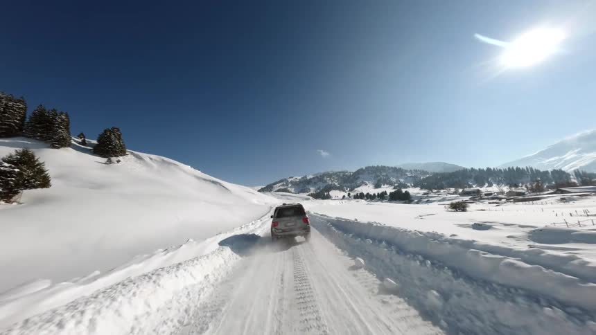 An suv drives along a snowy remote road on a sunny winter day