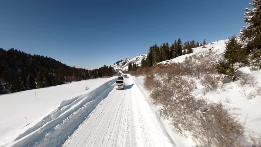 Trucks travel on a snow covered forested mountain road on a winter day