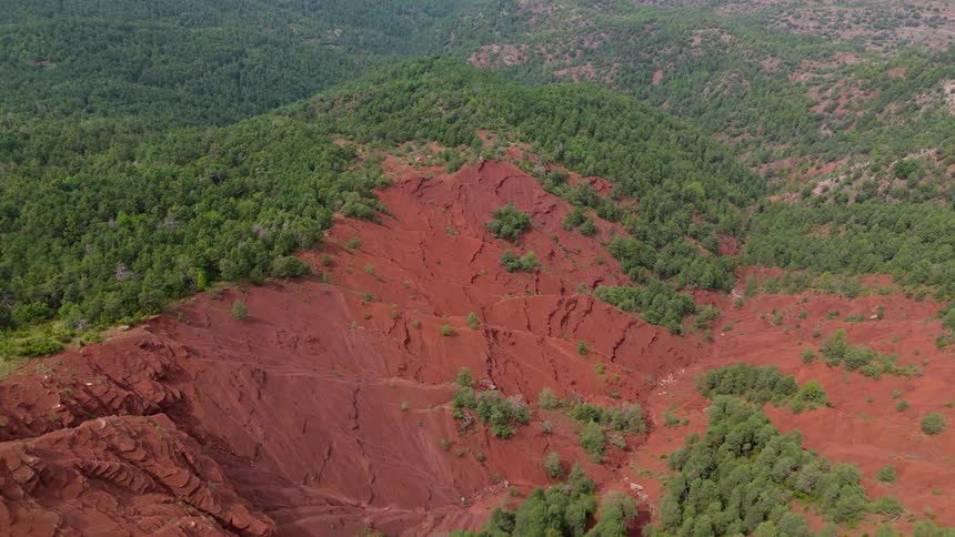Aerial of a forested mountain range with red clay soil