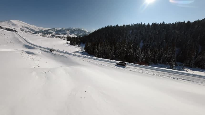 Trucks travel on a snow covered forested mountain road on a winter day