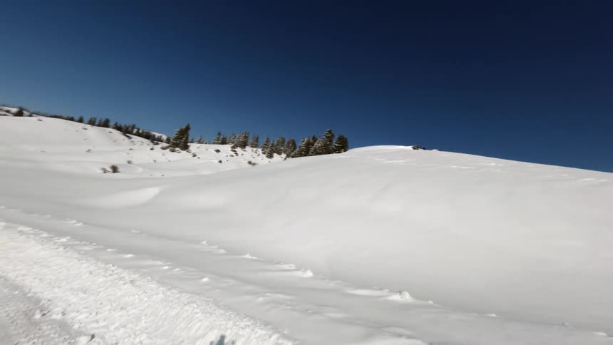 Two sports utility vehicles are driving across a snow covered landscape
