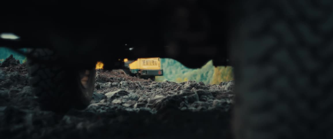 Vehicle traveling on rough terrain near the forest on an autumn day passes a parked vehicle