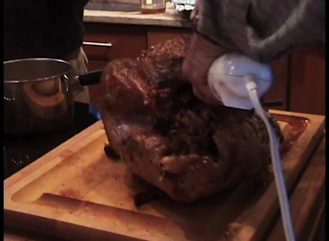 The man is carving the turkey with an electirc knife