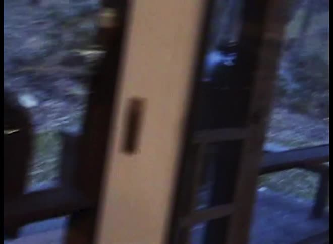 Father uses an electric carving knife to plate turkey at home while an outdoor smoker stands on the porch