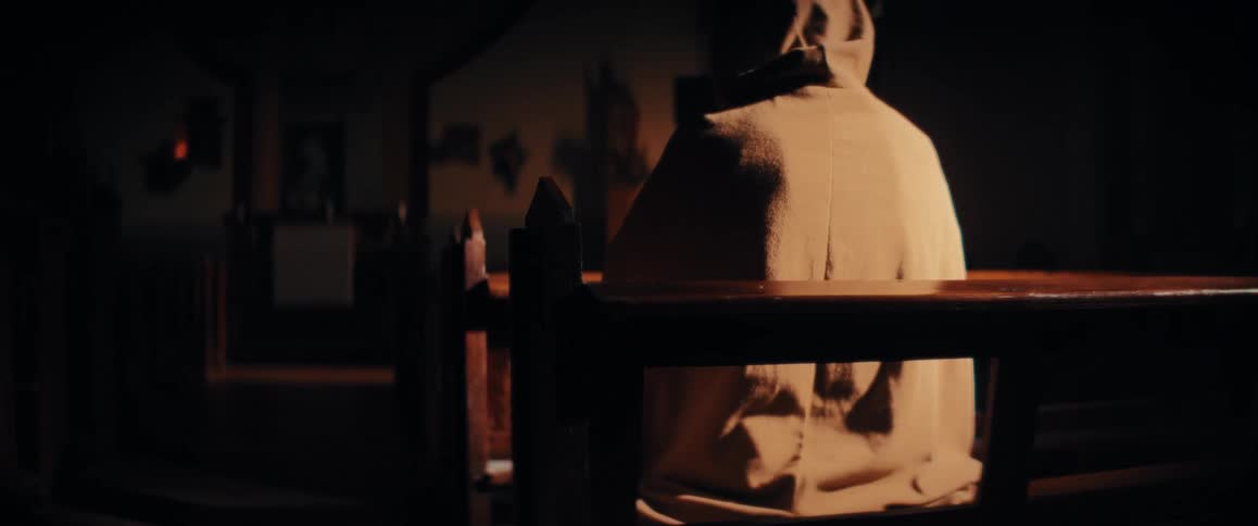 Person seated on wooden pew inside church
