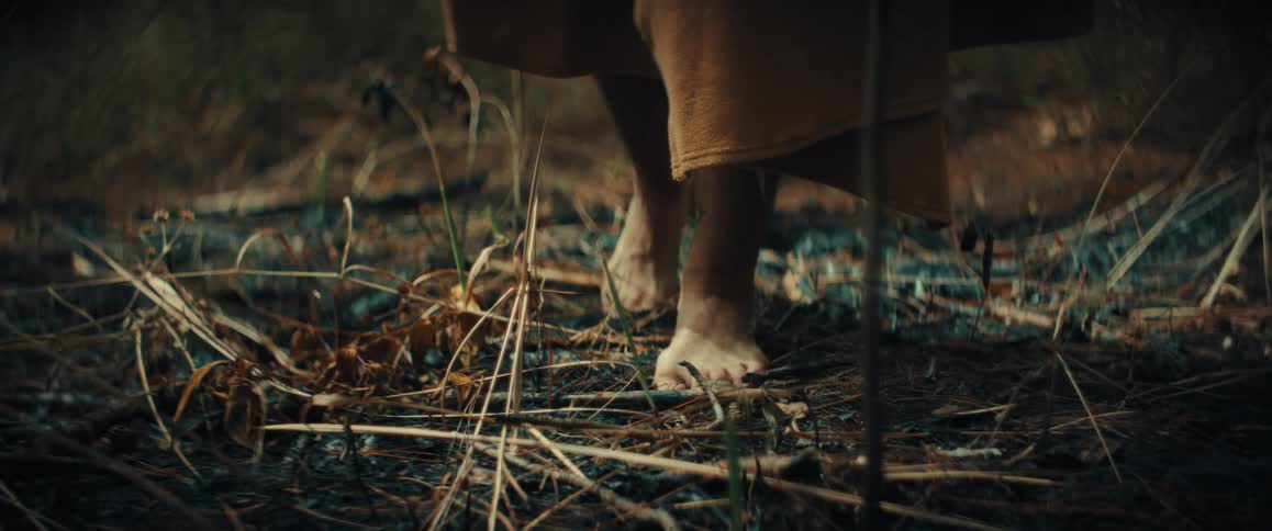 The man is hiking barefoot on the field