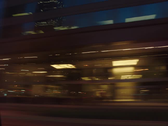 City buildings and street lights viewed from moving vehicle at night with motion blur