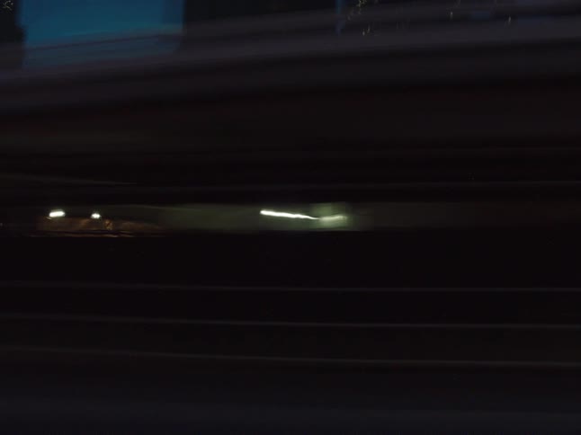 Cars pass by the tall buildings at night