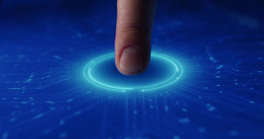 An index finger pressing onto a glowing circular button on a blue digital interface triggering light to flow through intricate circuitry patterns across a dark glass surface in a close up shot of futuristic technology