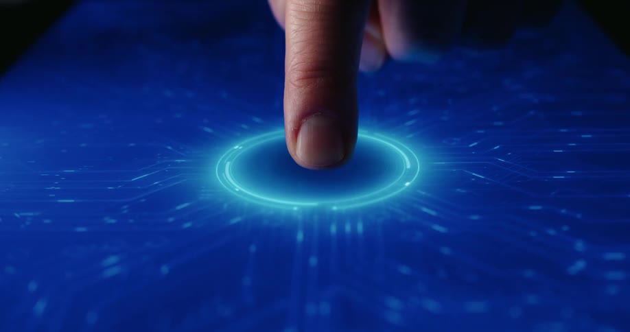 A man presses his index finger onto a glowing circular button on a blue digital touch screen that features intricate glowing circuitry patterns spreading across a dark surface