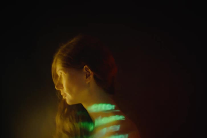 A woman with long wavy hair has words projected onto her back