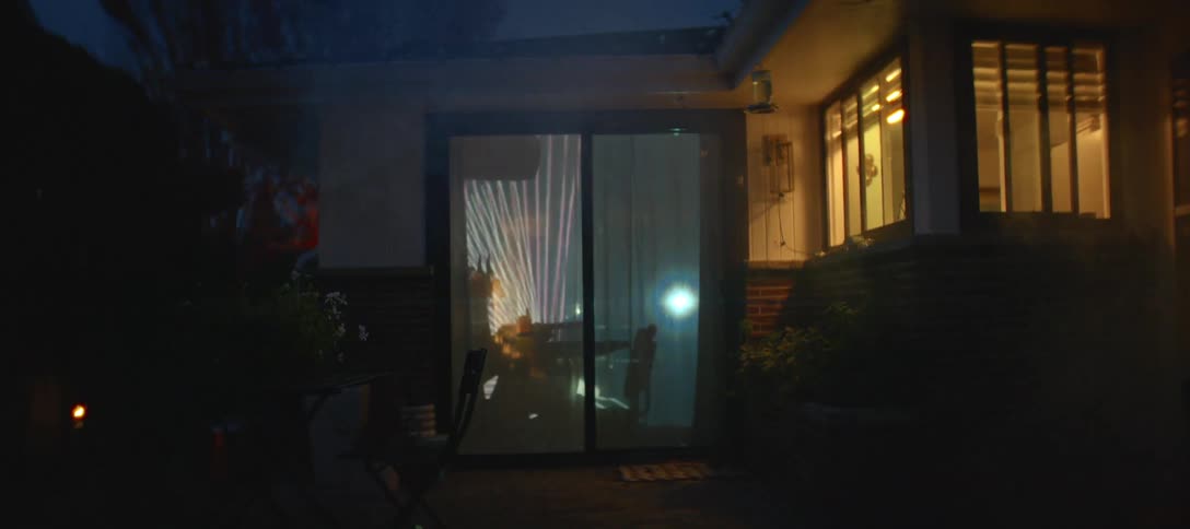 Outdoor projector creates patterns on the sliding glass doors at night
