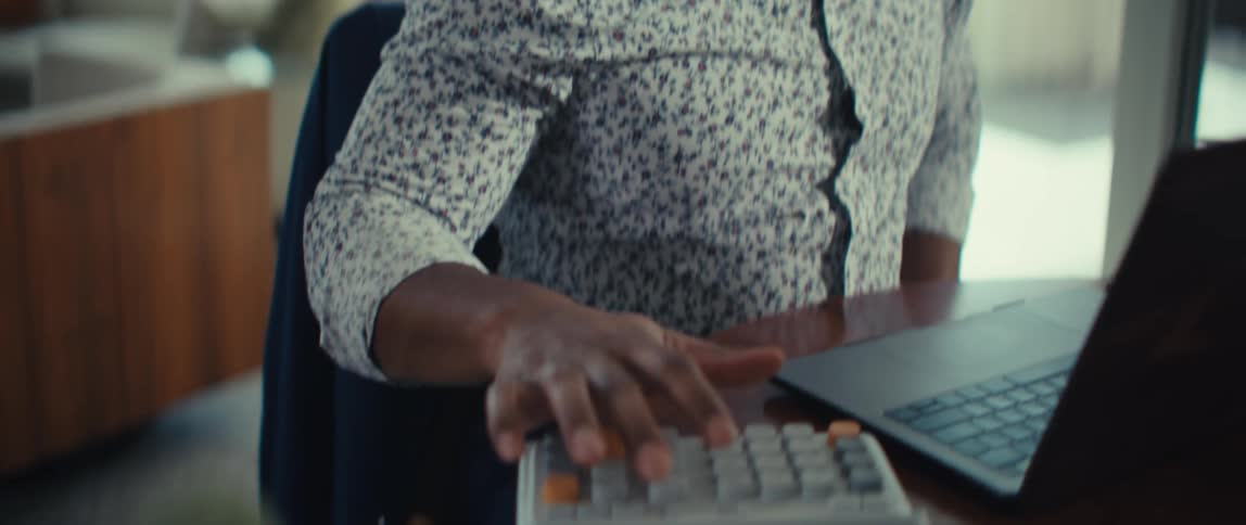 A man is using a calculator and a laptop in an office setting