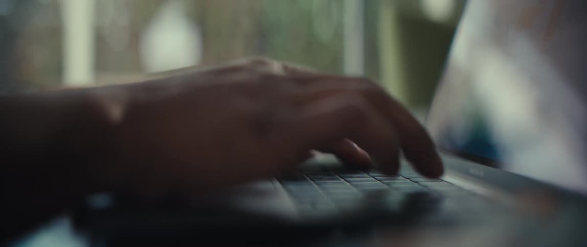 Hand typing on a laptop keyboard in close focus