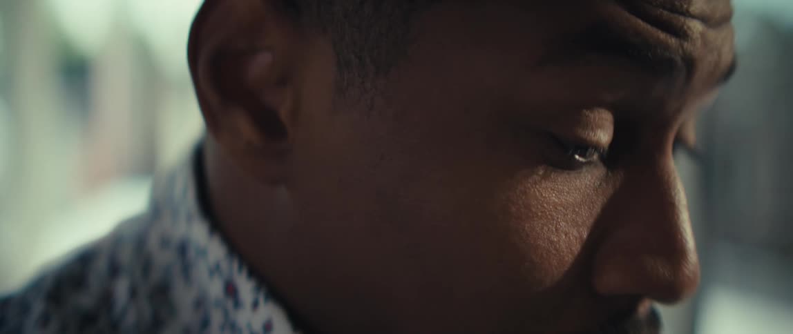 A man appears to be working intently beginning with a closeup of him rubbing his eyes and adjusting his glasses as if experiencing fatigue he then shifts his focus back to his task with the final shots showing his hands typing steadily on a laptop key
